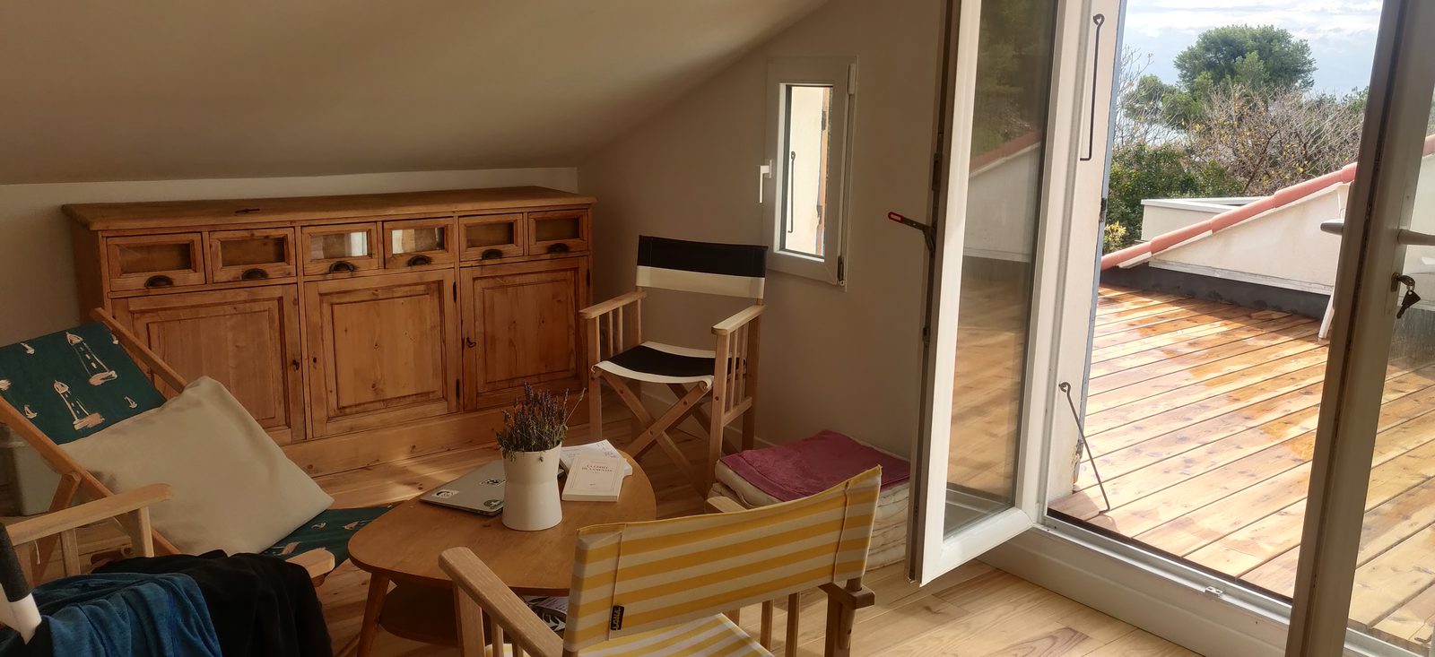 Le coin de la chambre avec sa table ronde, ses chaises de réalisateur et la porte ouverte sur la terrasse