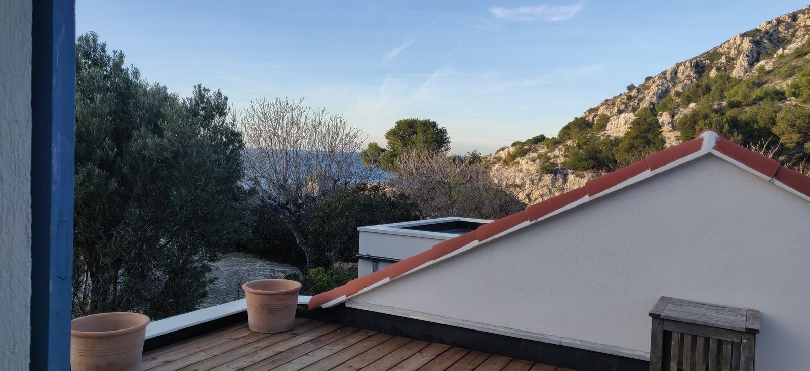La mer visible entre les arbres depuis le toit-terrasse de la Cabane, en hiver