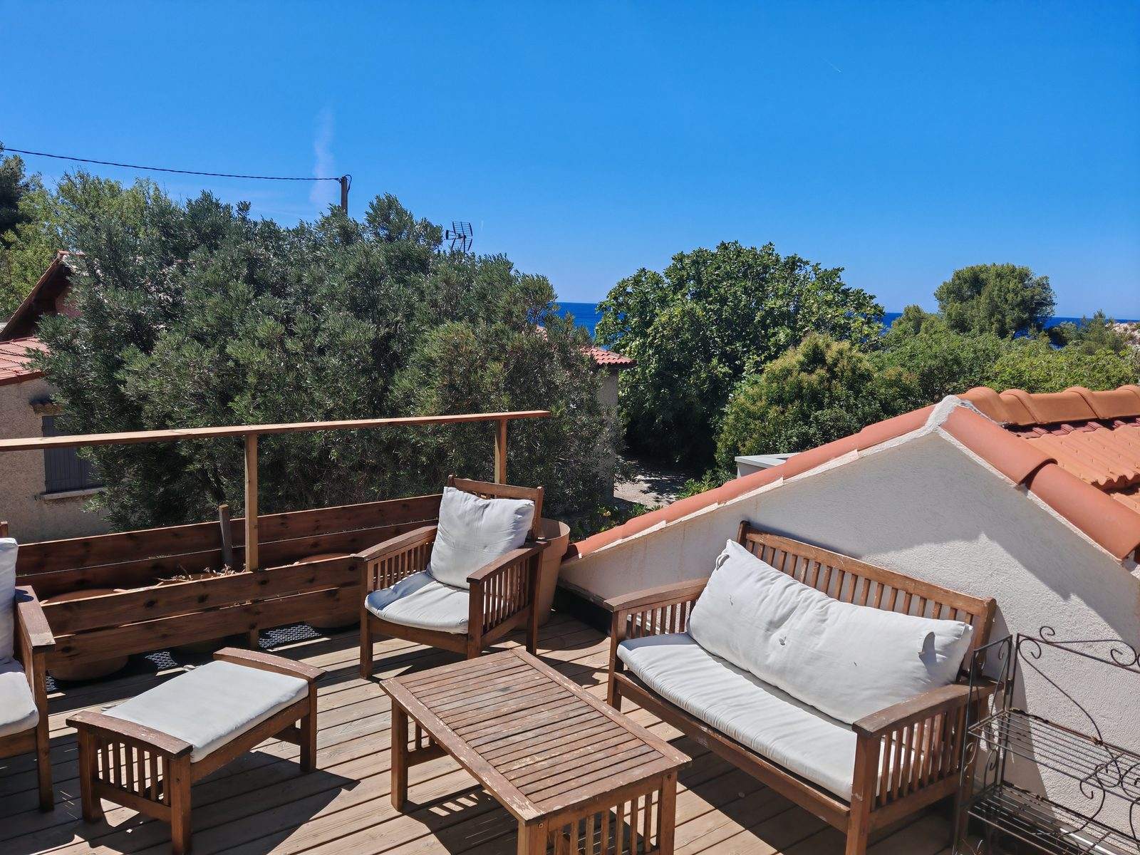 La Cabane de Niolon : le toit-terrasse en bois et la mer entre les arbres