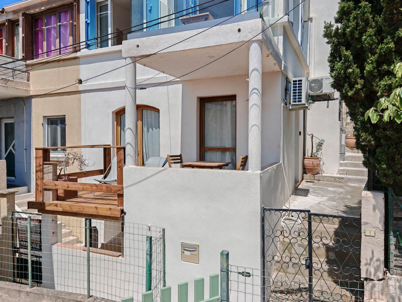 La Cabine de Niolon vue de la ruelle : la terrasse en bois en surplomb et la porte cintrée