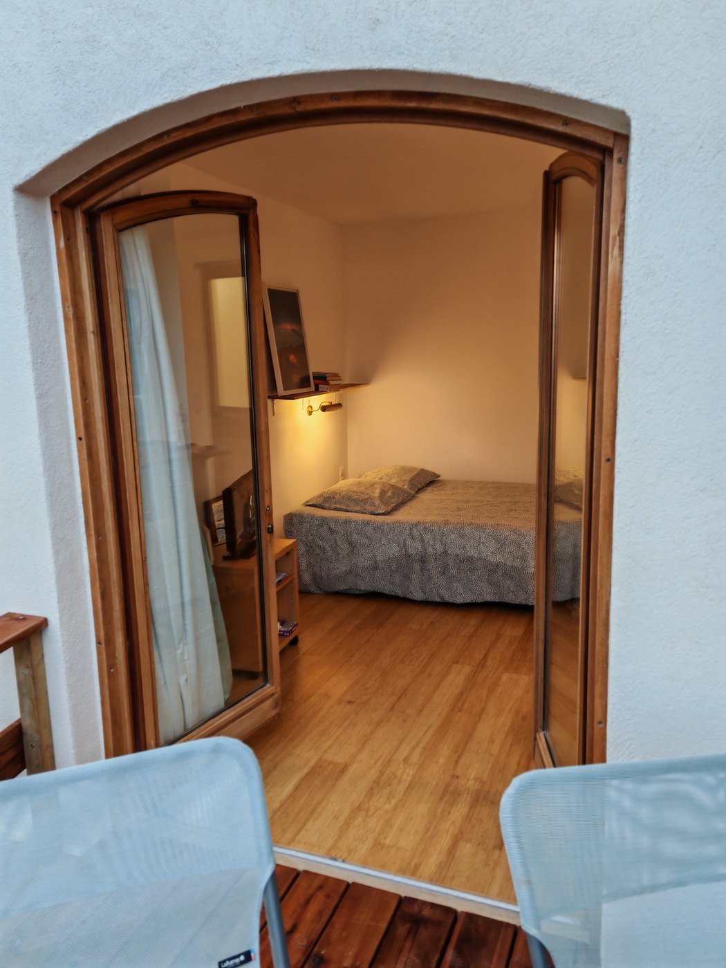 Le lit vu depuis la terrasse, à travers la porte cintrée, à la lampe