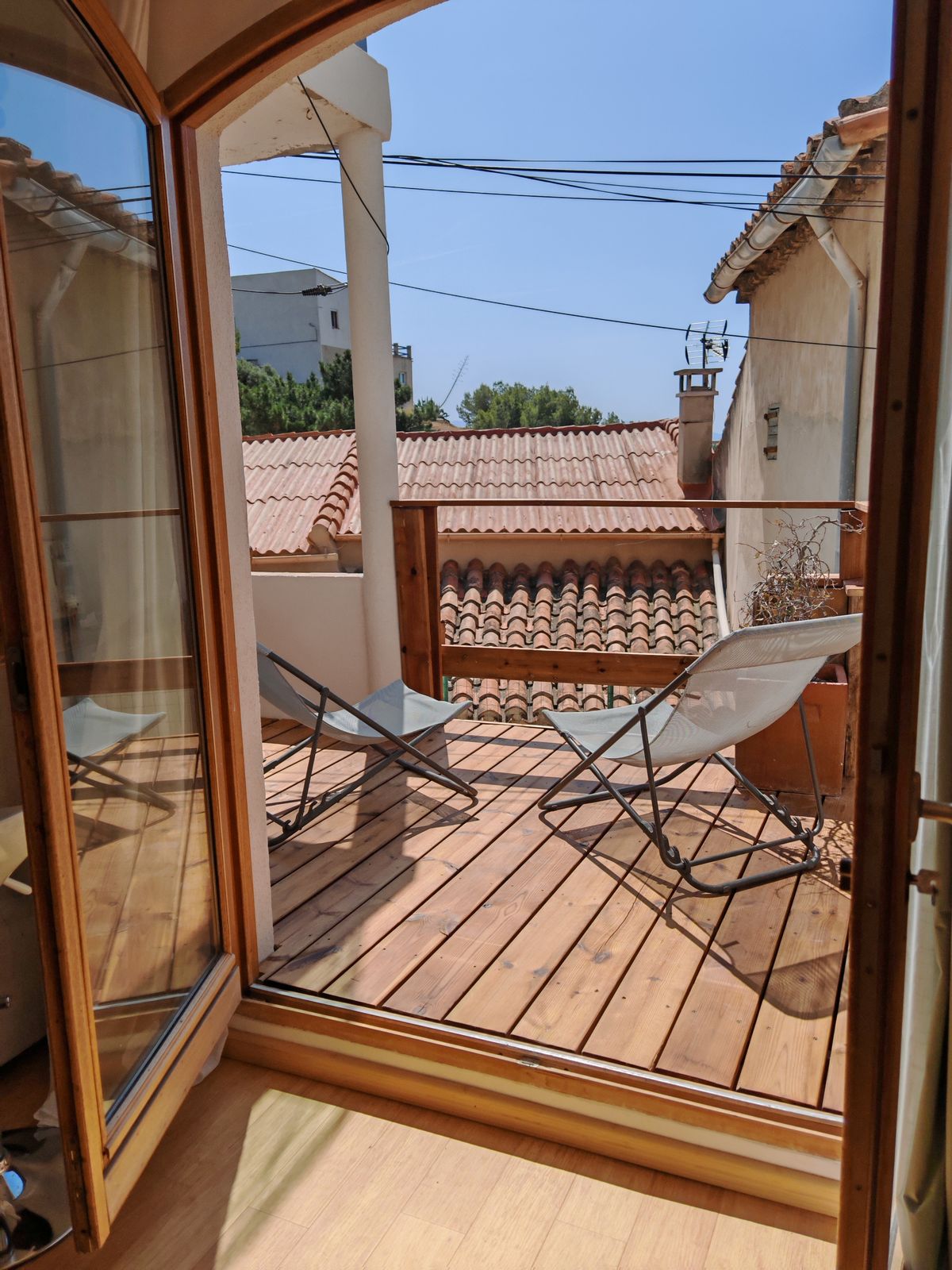 La porte cintrée ouverte sur la terrasse en bois et les toits du village