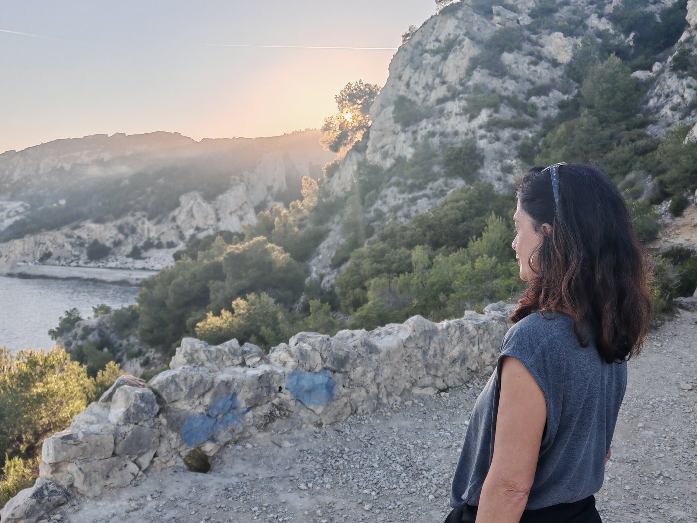 Une marcheuse sur le sentier des douaniers au soleil couchant